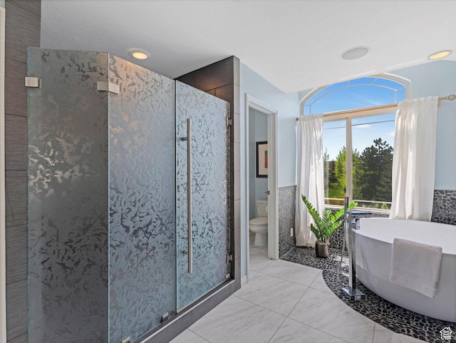 bathroom featuring a shower stall, toilet, and a freestanding tub