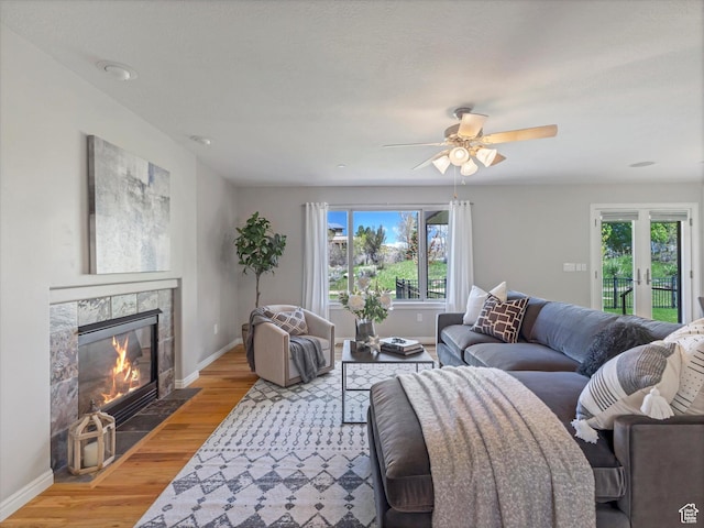 living area featuring healthy amount of natural light, baseboards, light wood finished floors, and a tile fireplace