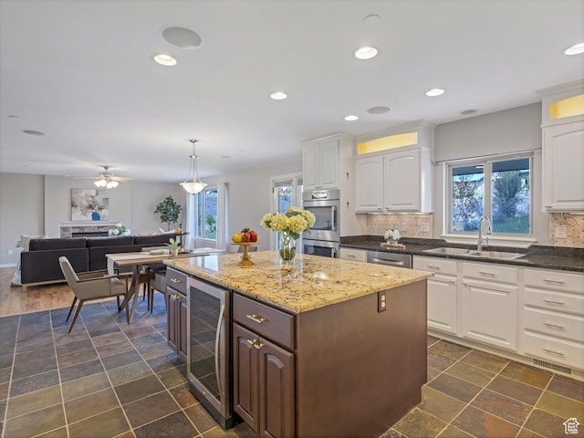 kitchen with a sink, beverage cooler, stainless steel appliances, healthy amount of natural light, and recessed lighting