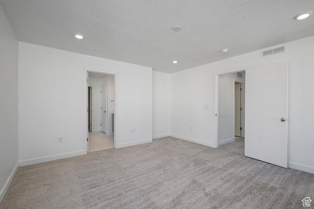 empty room featuring carpet flooring, a textured ceiling, recessed lighting, and baseboards