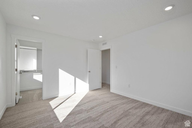 unfurnished bedroom featuring carpet floors, a walk in closet, recessed lighting, baseboards, and a closet