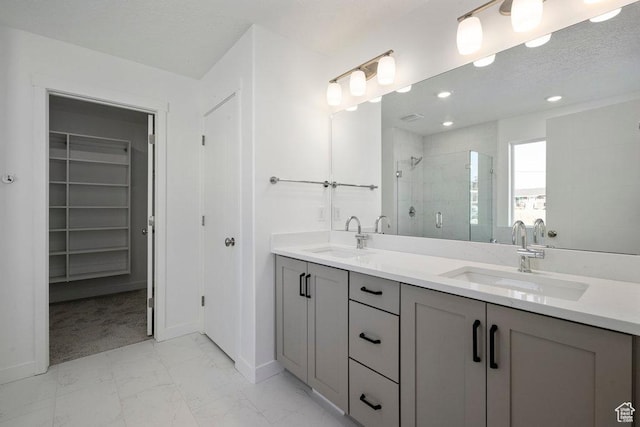 bathroom with a shower stall, marble look tiles, a spacious closet, double vanity, and baseboards