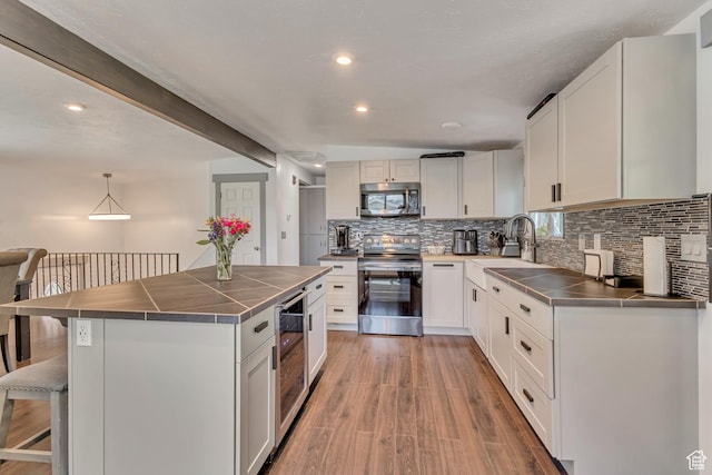 kitchen with range with electric stovetop, stainless steel microwave, a sink, beverage cooler, and a breakfast bar