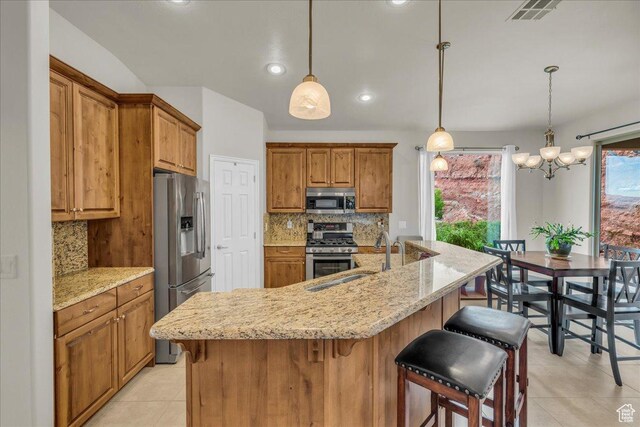 1668 W Lakota Dr, St George, UT 84770 - kitchen with stainless steel appliances, light tile patterned floors, a sink, decorative backsplash, and brown cabinetry