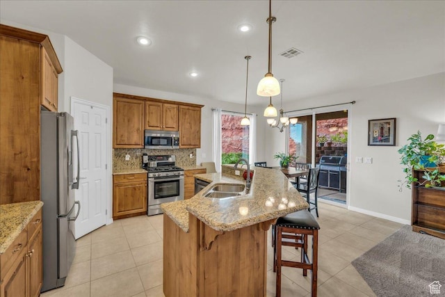 1668 W Lakota Dr, St George, UT 84770 - kitchen featuring stainless steel appliances, a sink, brown cabinets, light tile patterned floors, and a kitchen breakfast bar