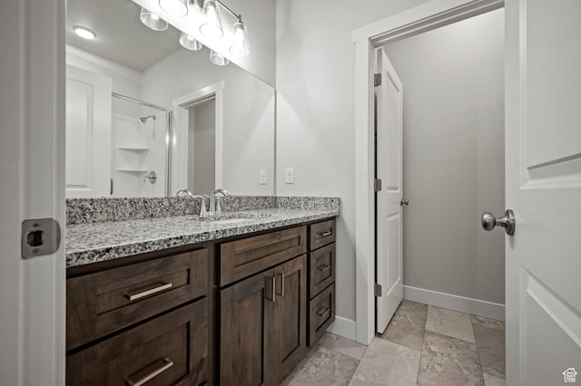 bathroom with baseboards, vanity, and a shower