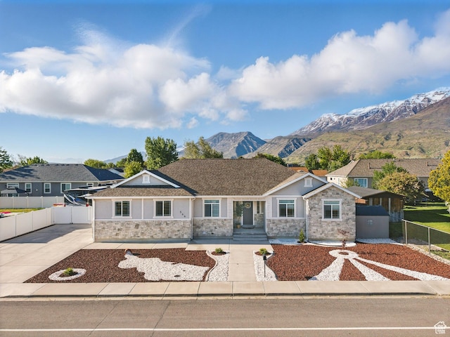 view of front facade with stone siding, fence, a mountain view, stucco siding, and concrete driveway