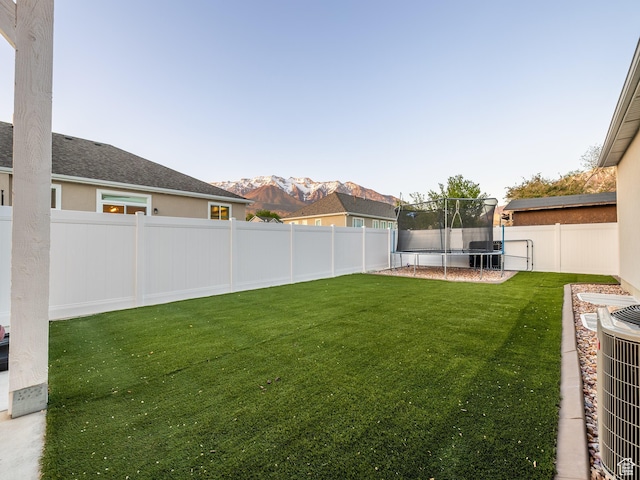view of yard with a trampoline and a mountain view