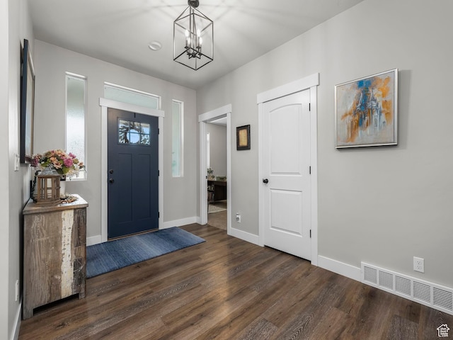 foyer entrance with dark wood-style floors, a chandelier, and baseboards