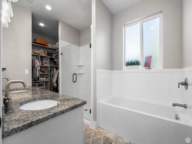 bathroom featuring a shower stall, a walk in closet, a garden tub, vanity, and recessed lighting