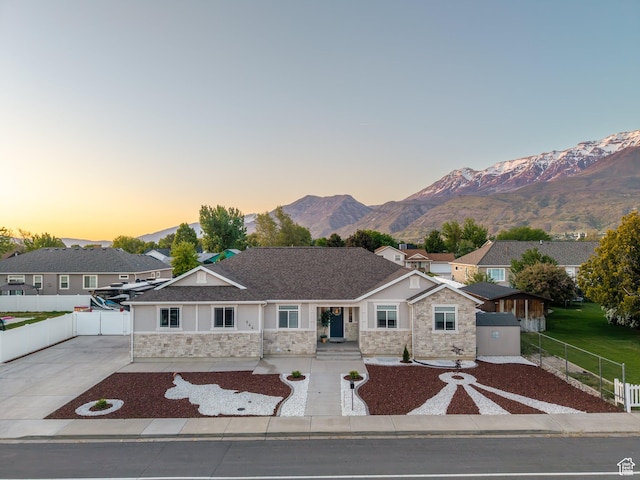 view of front of house featuring stone siding, concrete driveway, stucco siding, and a mountain view