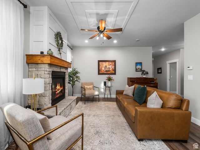 living room featuring a stone fireplace, wood finished floors, recessed lighting, baseboards, and ceiling fan