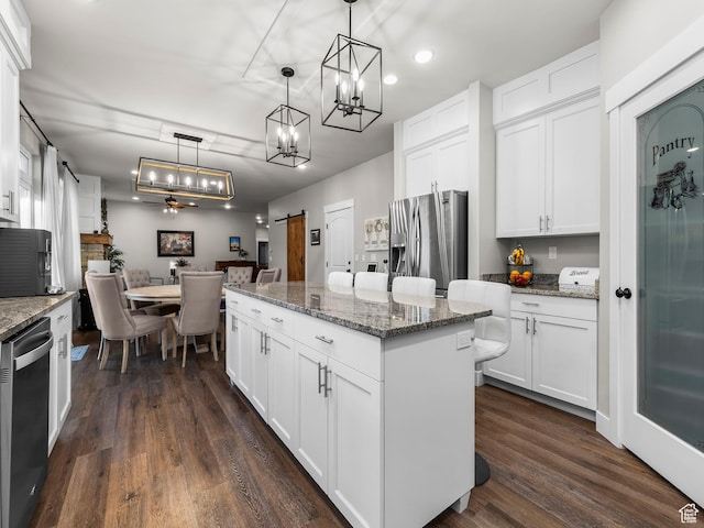 kitchen with appliances with stainless steel finishes, a kitchen island, a chandelier, dark wood finished floors, and recessed lighting