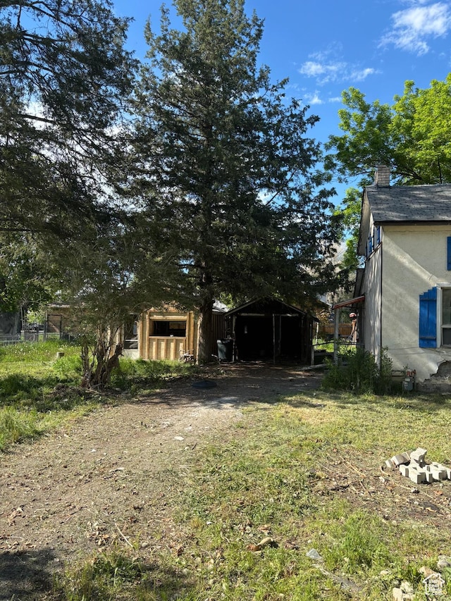 view of yard with a detached carport and dirt driveway
