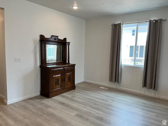 2055 S 4140 W, Taylor, UT 84401 - unfurnished living room featuring light wood finished floors, baseboards, and a textured ceiling