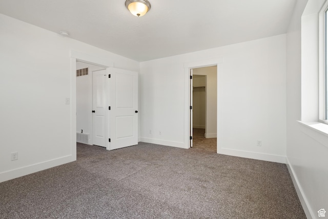 unfurnished bedroom with carpet flooring, baseboards, a spacious closet, and a closet