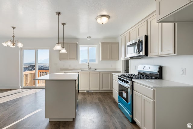 kitchen featuring stainless steel appliances, a sink, dark wood-type flooring, light countertops, and pendant lighting