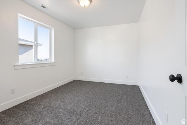 unfurnished room featuring dark colored carpet and baseboards