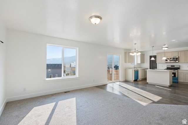 unfurnished living room featuring healthy amount of natural light, dark carpet, and baseboards