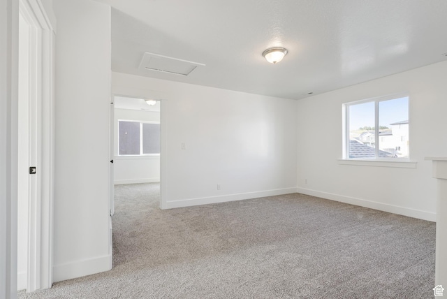 spare room with attic access, carpet, and baseboards