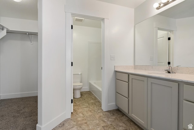 full bath with toilet, vanity, a walk in closet, and baseboards