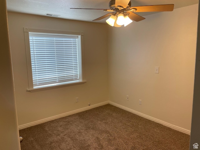 spare room featuring dark carpet, a ceiling fan, and baseboards