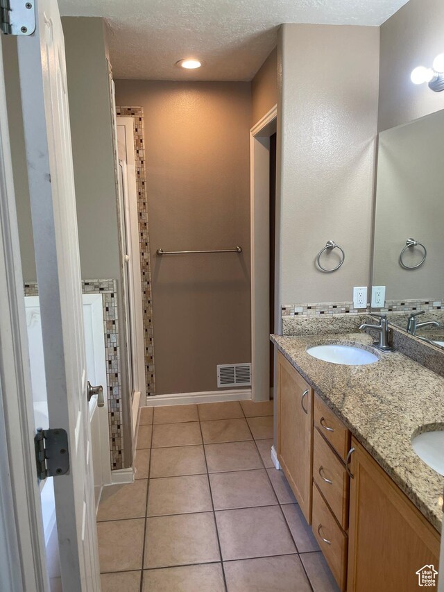 bathroom with tile patterned floors, double vanity, and a shower