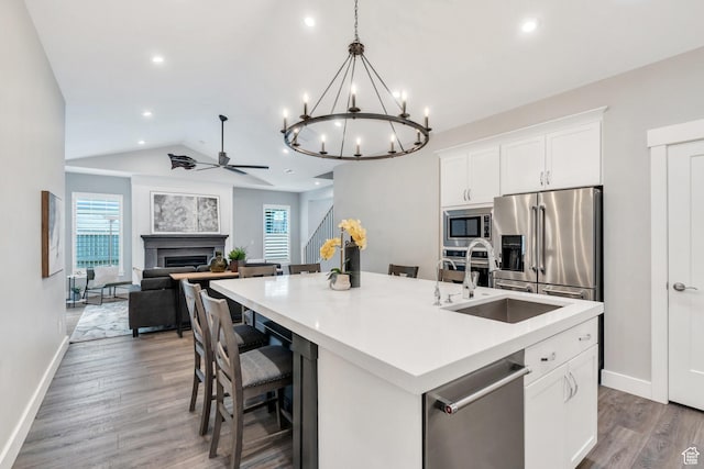 kitchen featuring stainless steel appliances, a fireplace, baseboards, a sink, and healthy amount of natural light