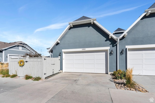 garage featuring driveway, a gate, and fence