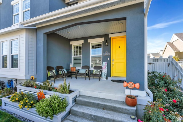 doorway to property with a porch, stucco siding, and fence