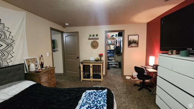 bedroom with a walk in closet, carpet flooring, a desk, a textured ceiling, and a closet