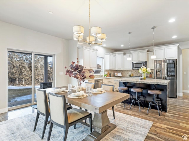 dining room featuring light wood finished floors, a chandelier, baseboards, and recessed lighting