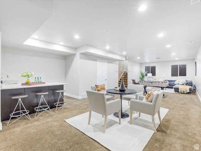 dining room featuring light carpet, recessed lighting, wet bar, and baseboards