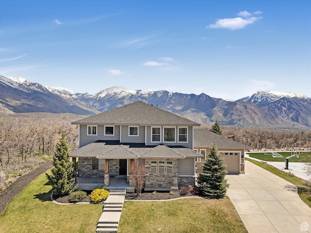 prairie-style home featuring concrete driveway, covered porch, a garage, stone siding, and a mountain view