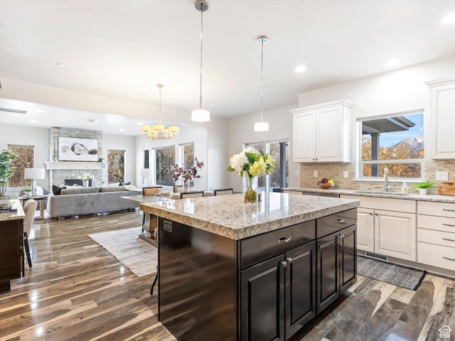 kitchen featuring wood finished floors, white cabinets, backsplash, a sink, and recessed lighting