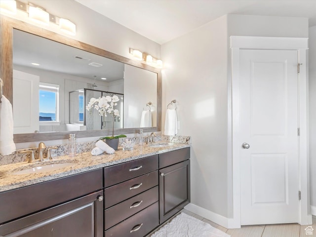 full bathroom featuring a shower stall, double vanity, baseboards, and tile patterned flooring