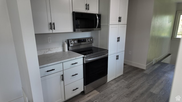kitchen with stainless steel appliances, light stone counters, dark wood-style flooring, and white cabinetry