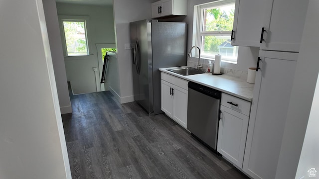kitchen with appliances with stainless steel finishes, a sink, healthy amount of natural light, and dark wood finished floors
