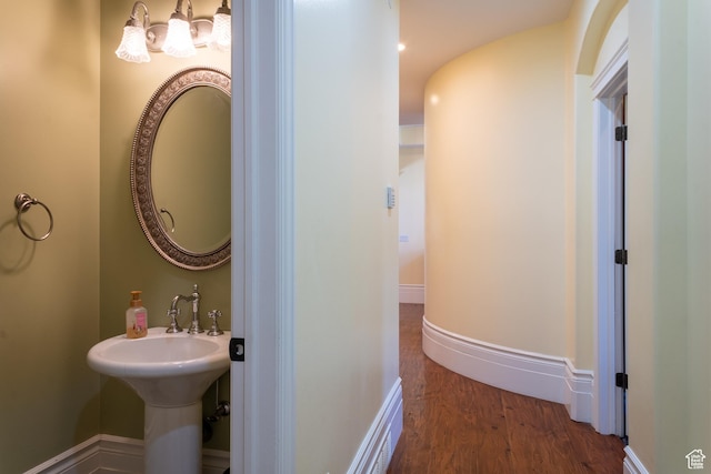 bathroom with wood finished floors, a chandelier, and baseboards