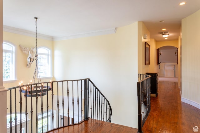 hallway with an upstairs landing, dark wood-type flooring, arched walkways, a chandelier, and recessed lighting