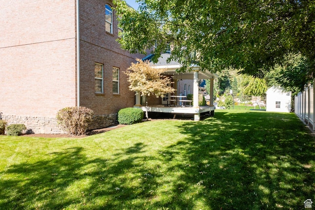 view of green lawn with a wooden deck