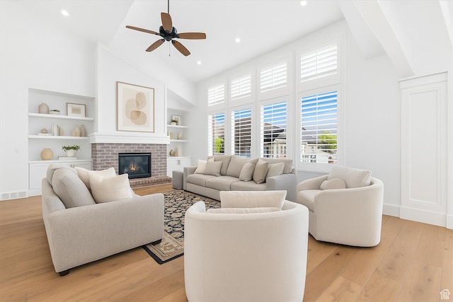 11896 S Verde View Cv, Riverton, UT 84065 - living area with high vaulted ceiling, light wood finished floors, a ceiling fan, built in features, and a brick fireplace