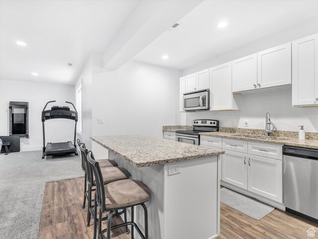 11896 S Verde View Cv, Riverton, UT 84065 - kitchen with stainless steel appliances, a kitchen island, a breakfast bar area, white cabinetry, and recessed lighting