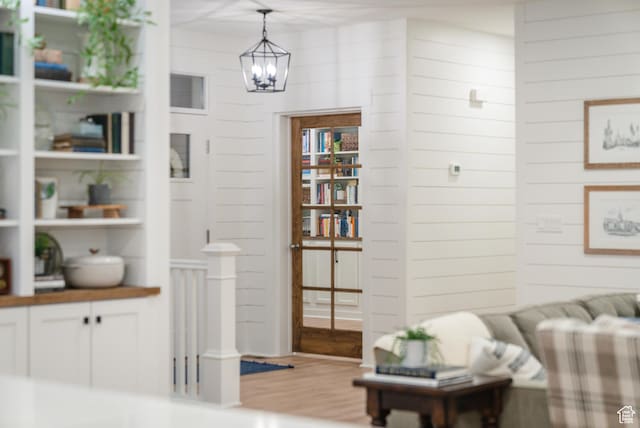 living area with wood finished floors, wood walls, and a chandelier