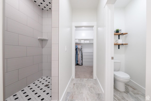 full bath with a stall shower, toilet, baseboards, and marble look tile flooring