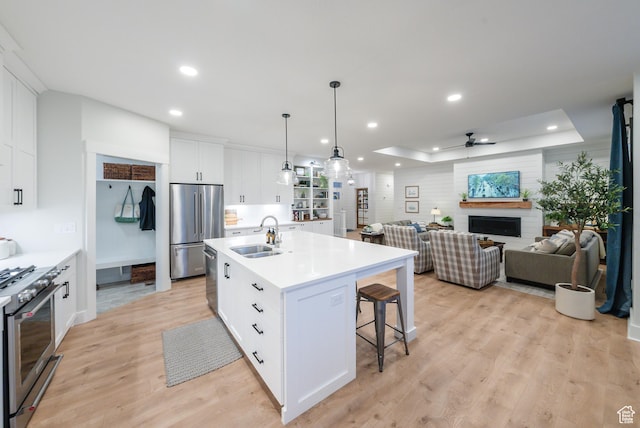 kitchen featuring premium appliances, a sink, a breakfast bar area, light wood-type flooring, and white cabinets