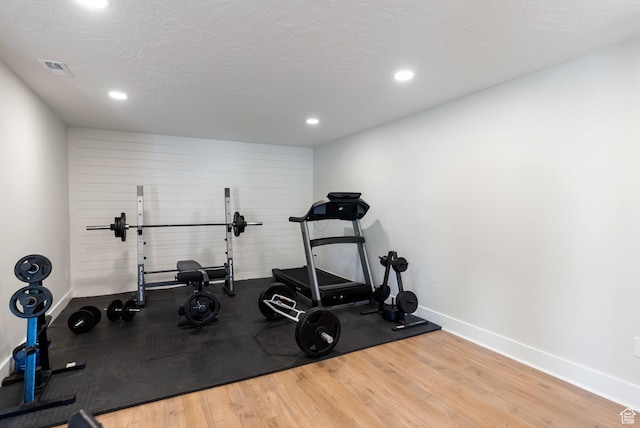 workout area featuring baseboards, wood finished floors, and recessed lighting