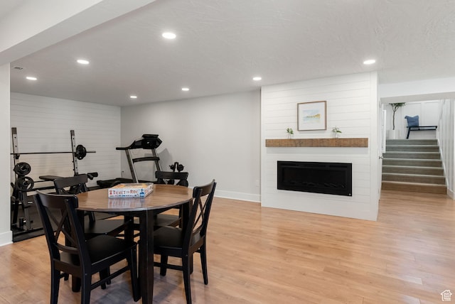 dining room featuring baseboards, light wood-style flooring, recessed lighting, a fireplace, and stairs