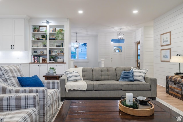 living room with wood finished floors, recessed lighting, a chandelier, and wood walls