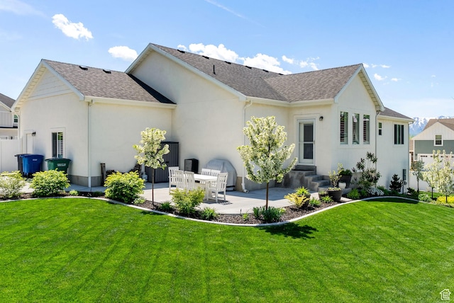 rear view of house with a patio, stucco siding, a lawn, roof with shingles, and entry steps